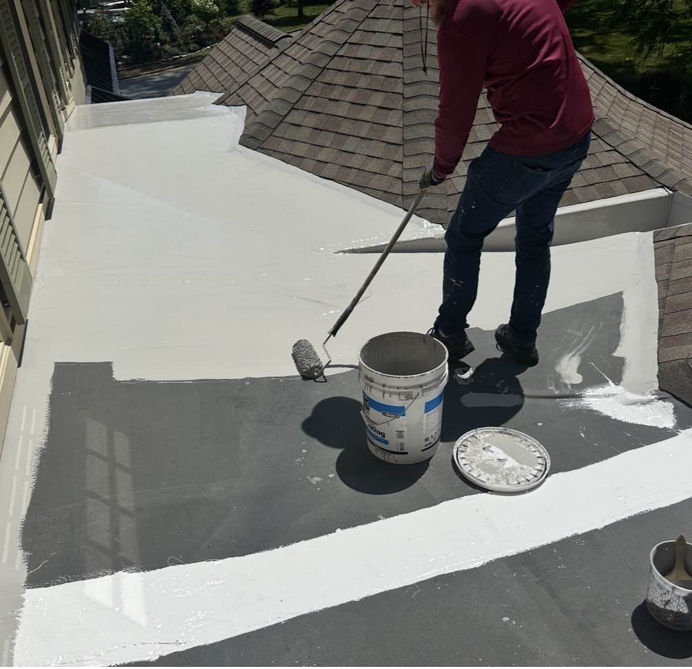 Rolling white silicone coating across a flat roof