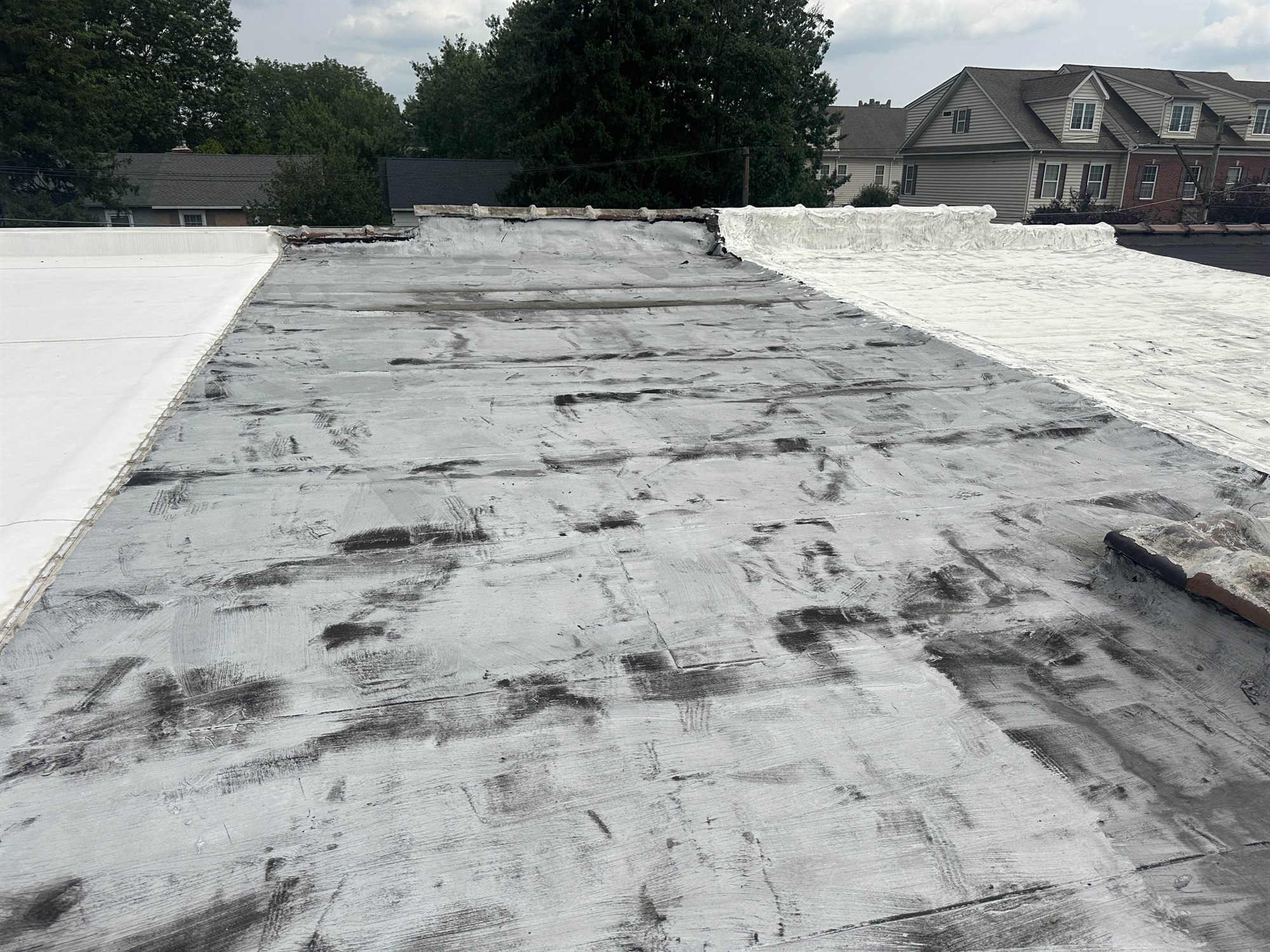 Lansdale PA flat roof before coating, weathered and patched membrane