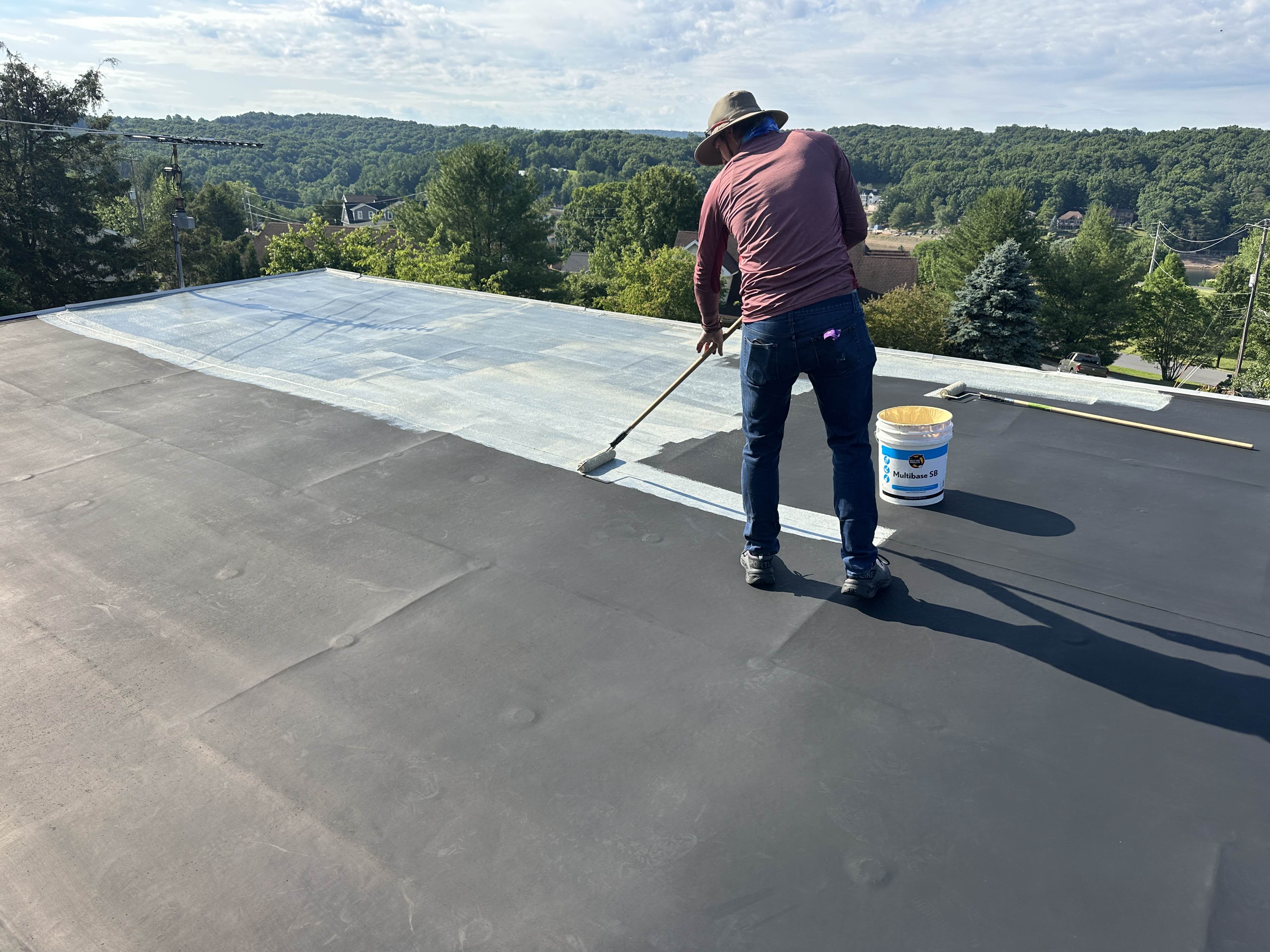 Rolling primer onto a prepped flat roof for coating adhesion