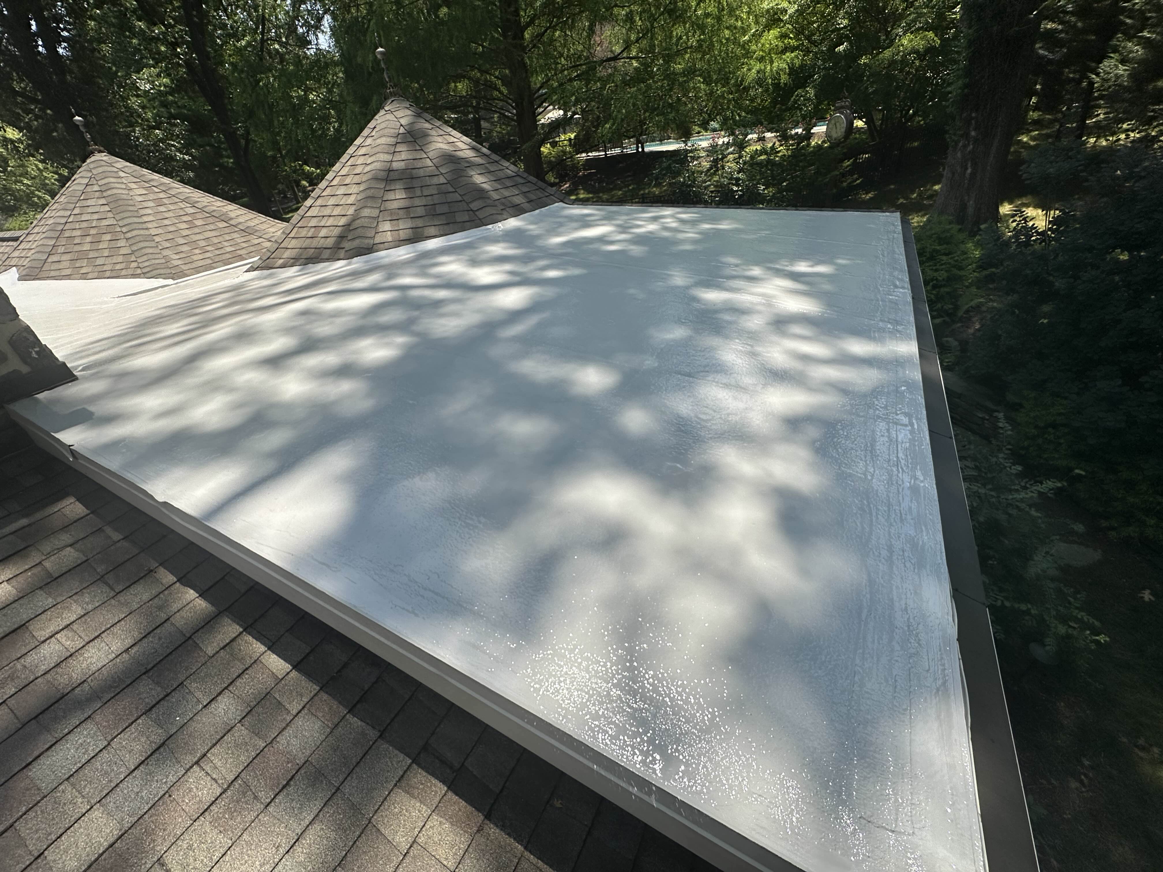 Completed silicone flat roof between two shingled roof sections