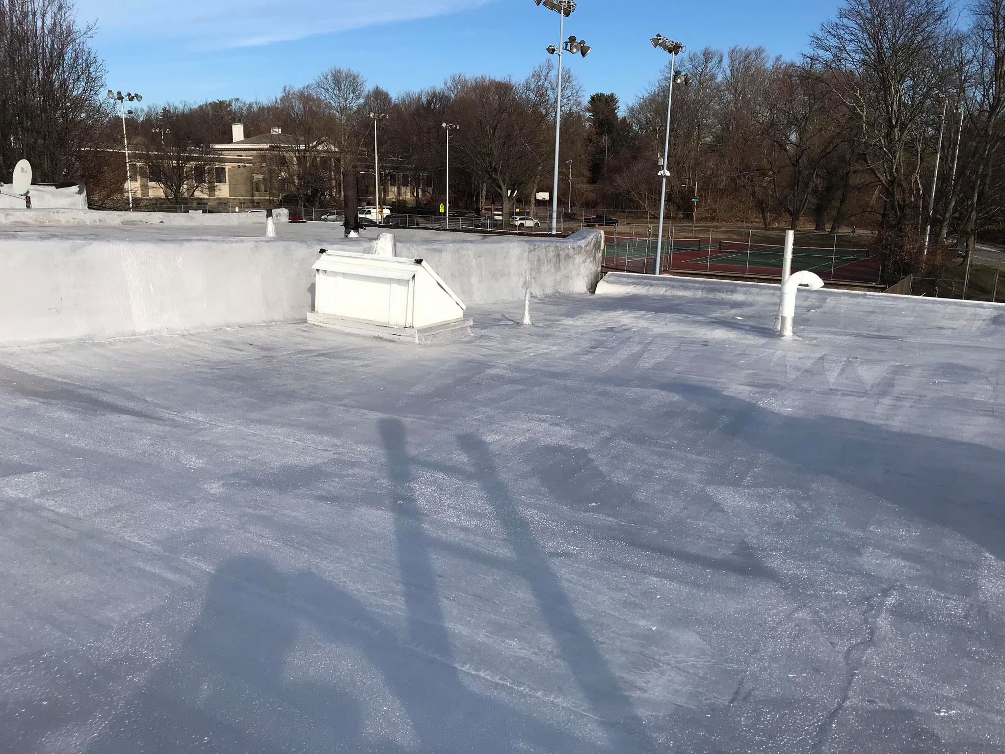Silver aluminum reflective roof coating completed on large flat commercial roof